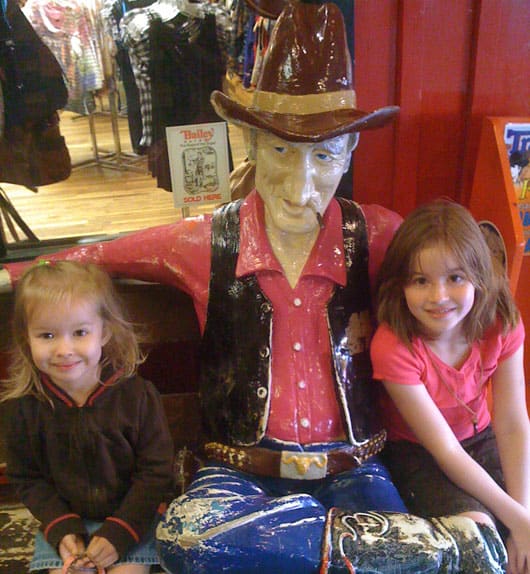 Soft, fluffy, and filled with blueberries, this family recipe makes a batch of the best blueberry muffins topped with a buttery streusel. two girls with a cowboy statue