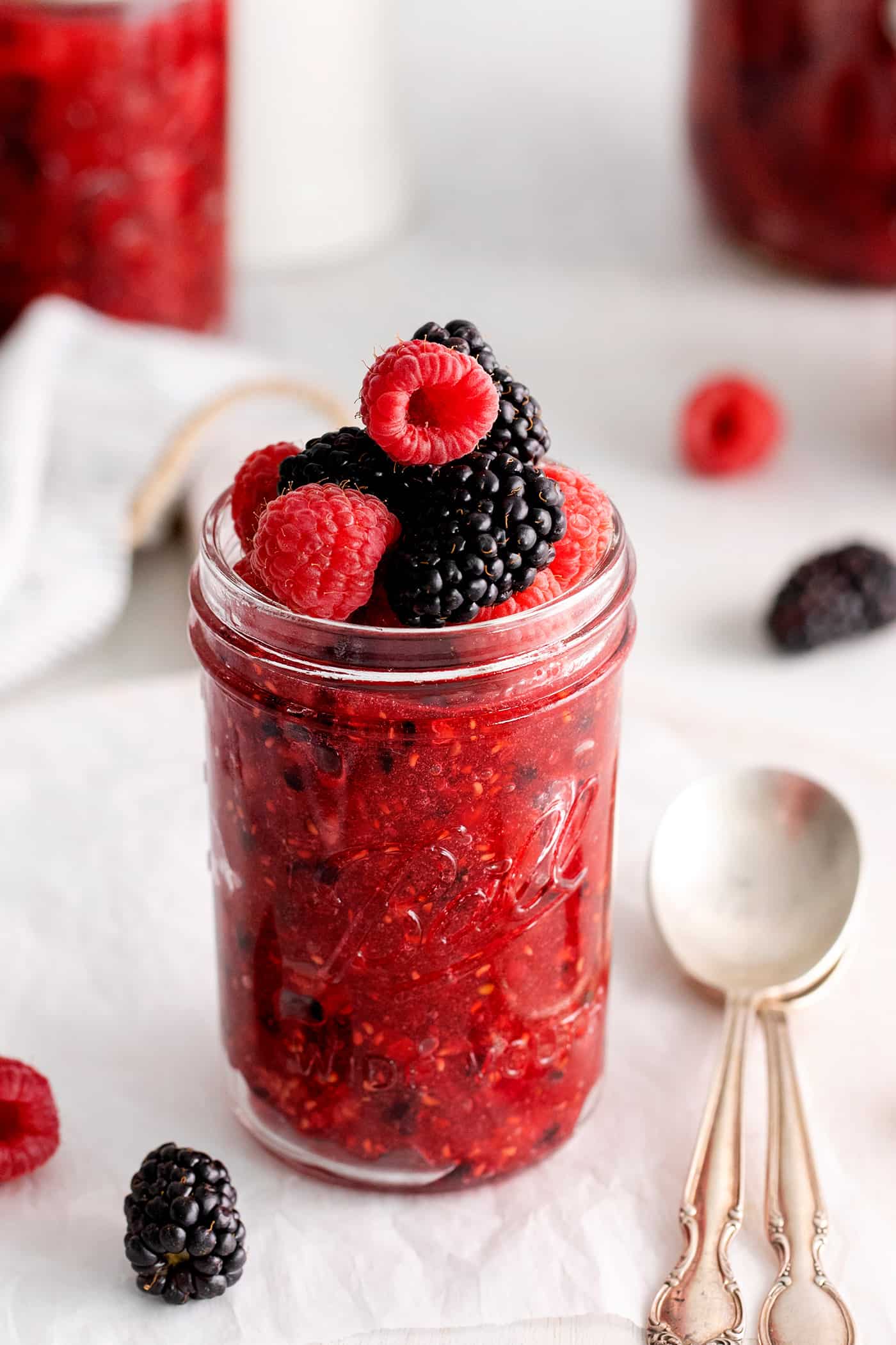 This Raspberry Blackberry Freezer Jam comes together in less than an hour, with just 4 ingredients. No cooking or canning is required! Angled view of a jar of raspberry blackberry freezer jam