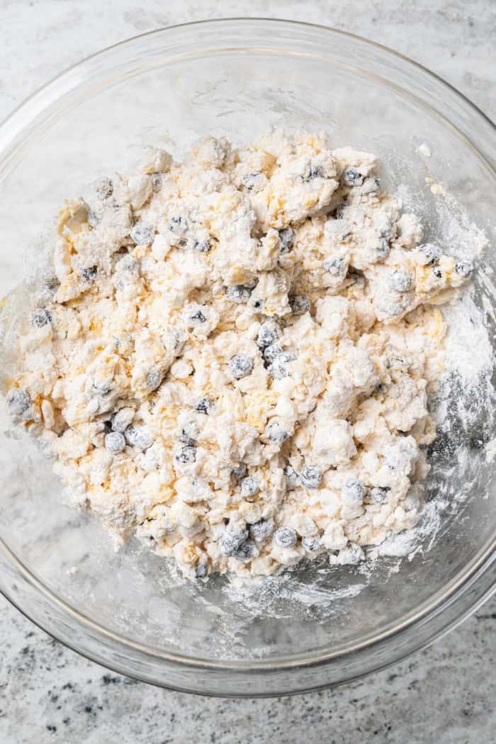 Rich, flaky and dotted with chewy dried blueberries, these blueberry scones are a bakery-style treat you can easily make at home! Overhead view of blueberry scone dough in glass mixing bowl