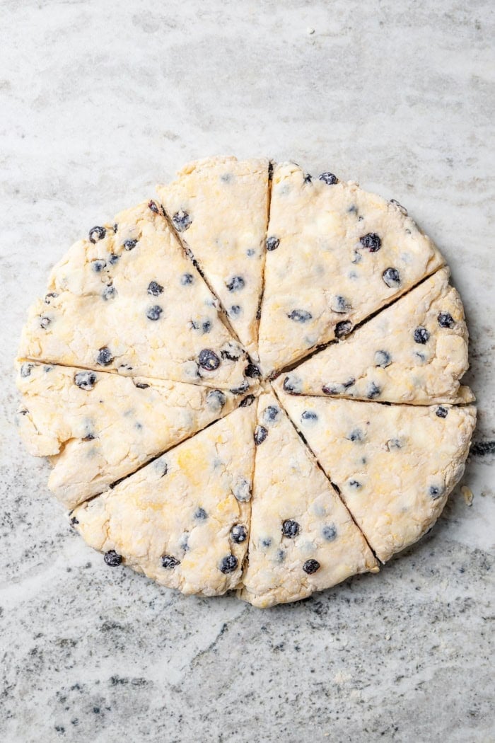 Overhead view of blueberry scones cut into wedges before baking