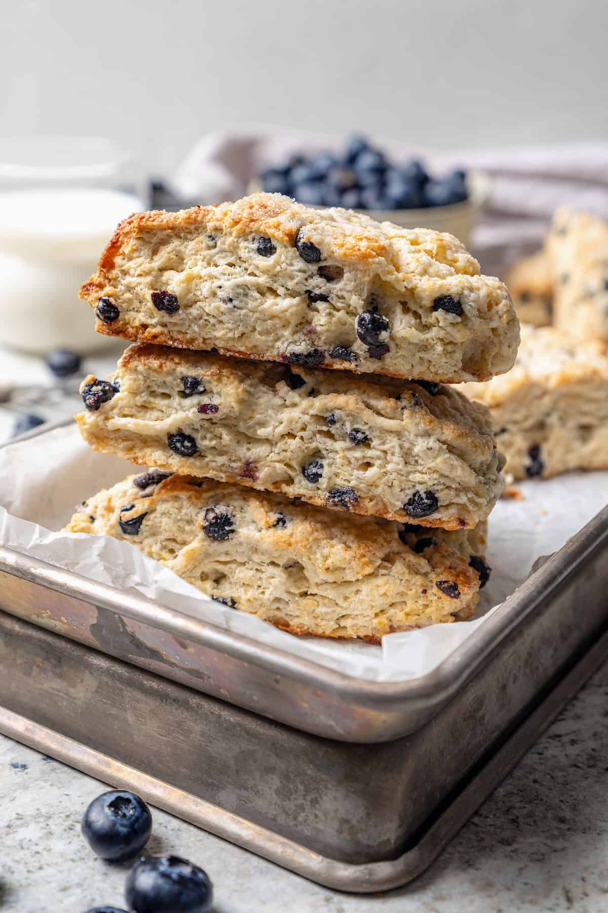 Rich, flaky and dotted with chewy dried blueberries, these blueberry scones are a bakery-style treat you can easily make at home! Stack of 3 homemade blueberry scones on baking sheet