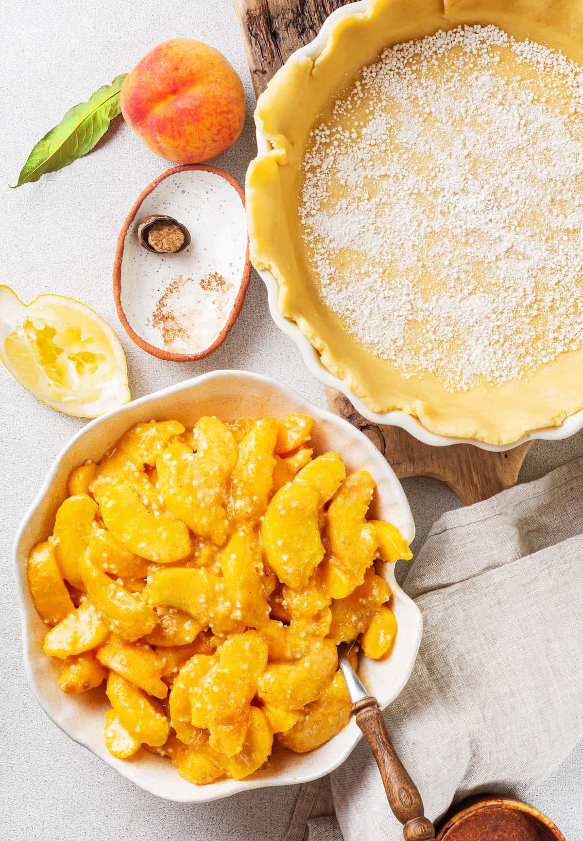 Made with just 10 ingredients, this Homemade Peach Pie is perfectly spiced and topped with a beautiful golden brown flaky lattice crust. A bowl of peach pie filling next to a pie crust