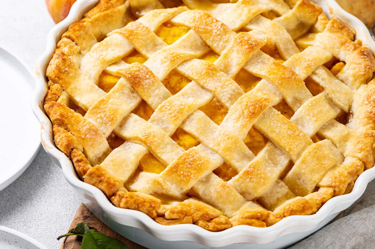Made with just 10 ingredients, this Homemade Peach Pie is perfectly spiced and topped with a beautiful golden brown flaky lattice crust. Overhead view of a homemade peach pie