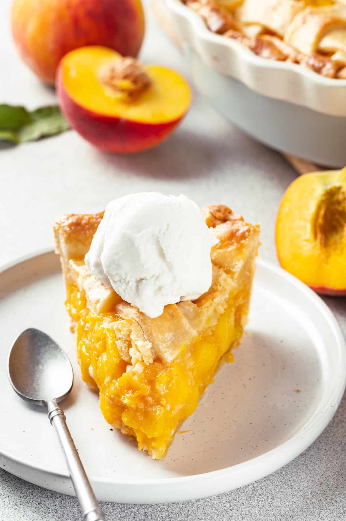 Made with just 10 ingredients, this Homemade Peach Pie is perfectly spiced and topped with a beautiful golden brown flaky lattice crust. A slice of peach pie topped with a scoop of ice cream