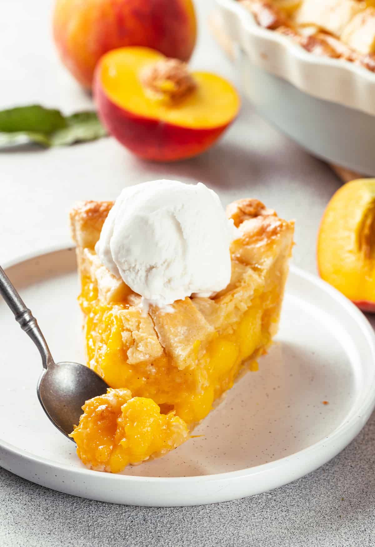 Made with just 10 ingredients, this Homemade Peach Pie is perfectly spiced and topped with a beautiful golden brown flaky lattice crust. A slice of peach pie topped with a scoop of ice cream