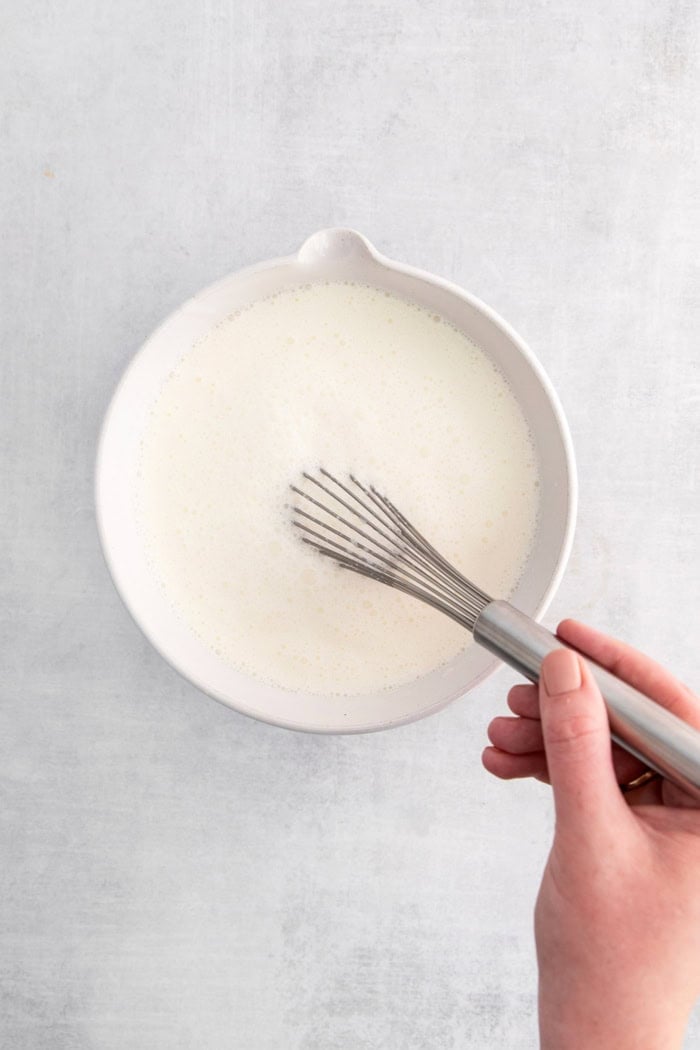 Ultra creamy homemade Coconut Ice Cream is pure summertime fun! You only need 3 simple ingredients to whip up this easy recipe. Whisking coconut ice cream ingredients in bowl