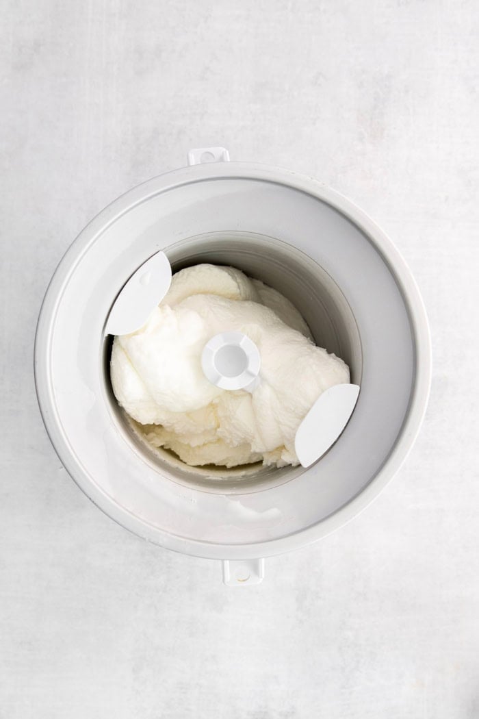 Ultra creamy homemade Coconut Ice Cream is pure summertime fun! You only need 3 simple ingredients to whip up this easy recipe. Overhead view of coconut ice cream churning in ice cream maker