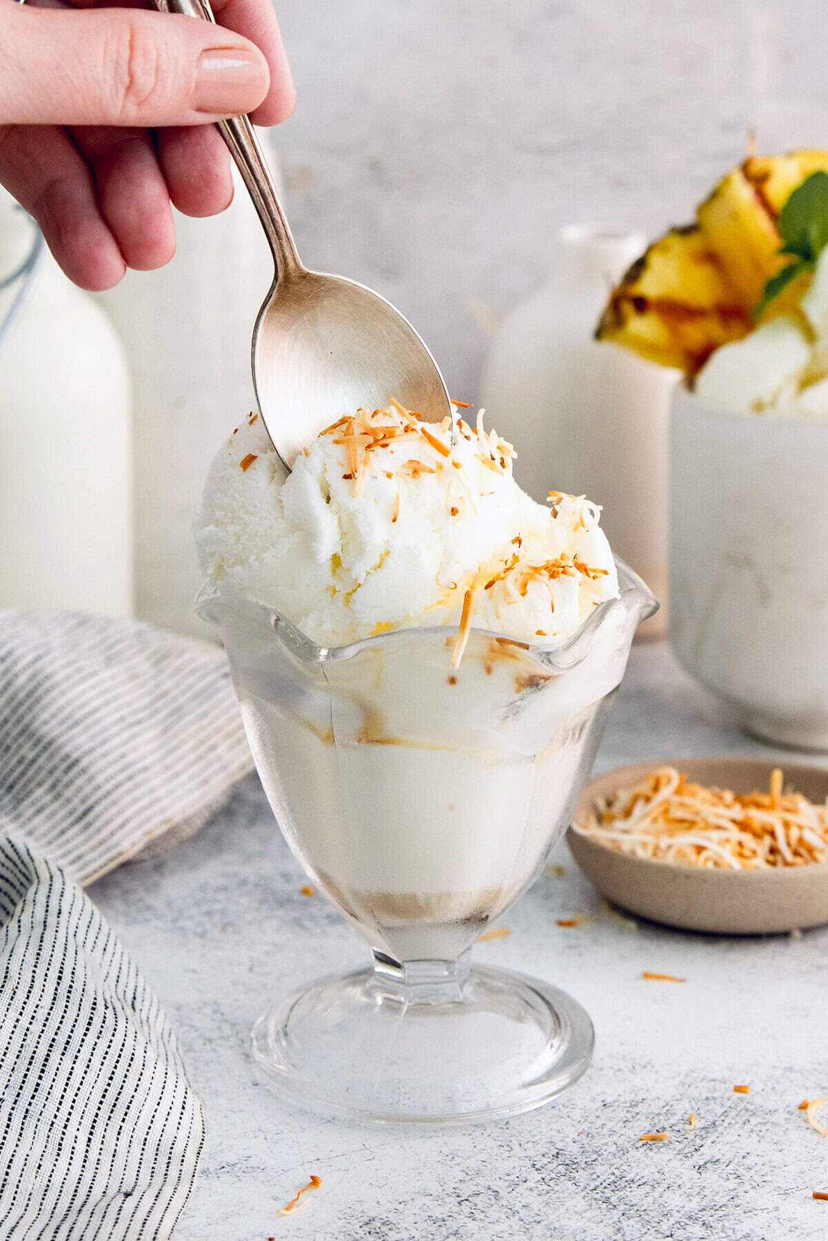 Ultra creamy homemade Coconut Ice Cream is pure summertime fun! You only need 3 simple ingredients to whip up this easy recipe. Spoon digging into coconut ice cream topped with toasted coconut