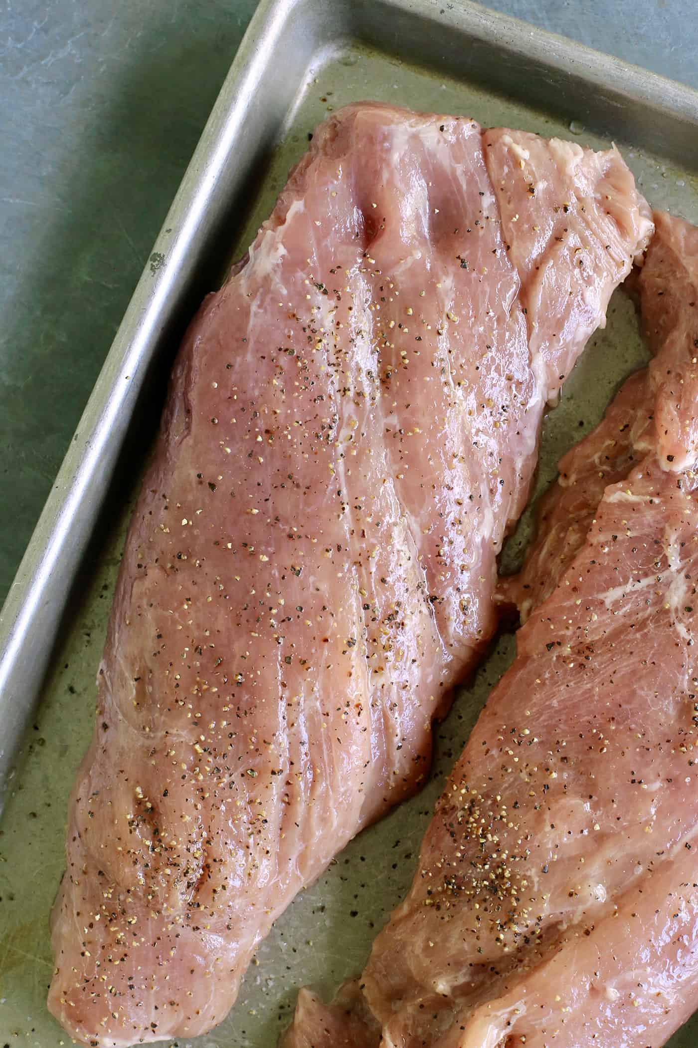 Tender, juicy Grilled Pork Tenderloin is glazed with a sweet peach sauce then topped with an orange-habanero mojo. Pork tenderloin on a baking sheet