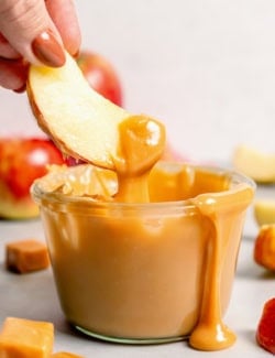 Dipping apple into jar of caramel apple dip