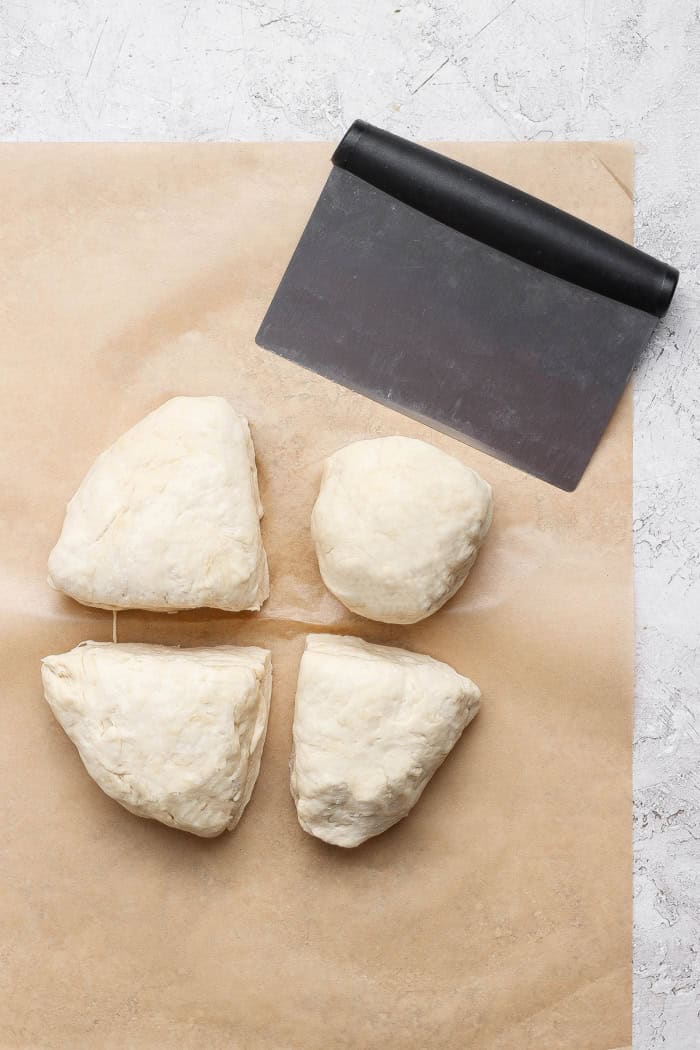 Dough divided into 4 portions with bench scraper.