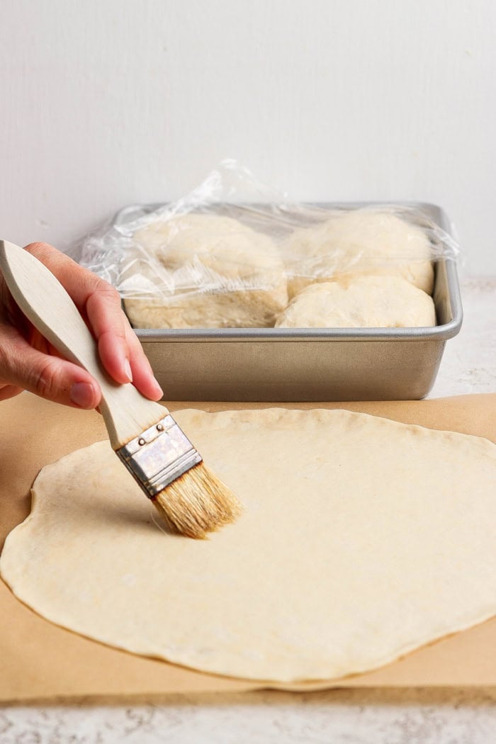 Brushing oil onto dough for pizza crust.