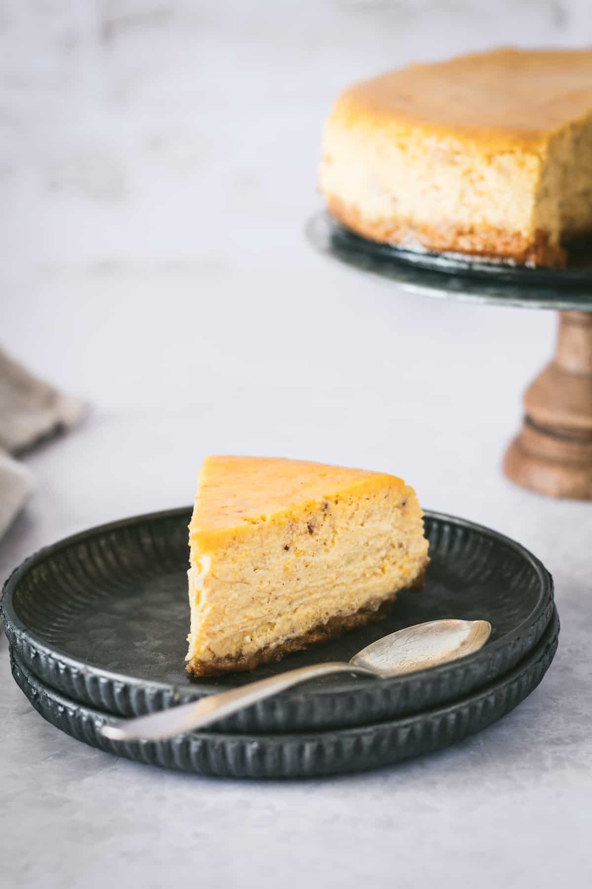 This is the best pumpkin cheesecake recipe! It's creamy, easy to make, and packed with pumpkin flavor, baked in a crunchy gingersnap crust. A slice of pumpkin cheesecake on a plate