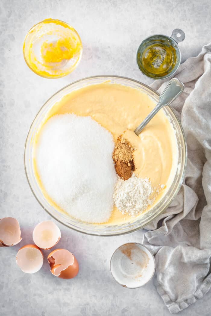 This is the best pumpkin cheesecake recipe! It's creamy, easy to make, and packed with pumpkin flavor, baked in a crunchy gingersnap crust. Sugar and spices added pumpkin cheesecake batter in a mixing bowl.