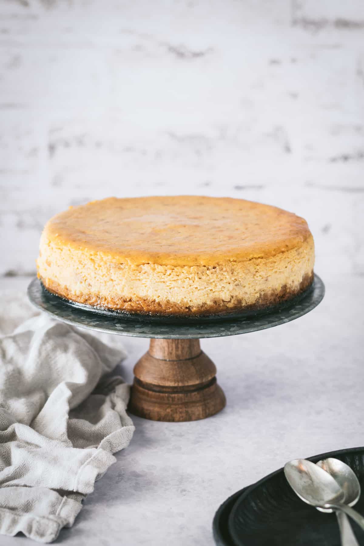 This is the best pumpkin cheesecake recipe! It's creamy, easy to make, and packed with pumpkin flavor, baked in a crunchy gingersnap crust. Creamy pumpkin cheesecake with gingersnap crust on a serving stand