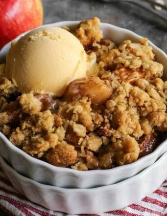 Homemade apple crisp in a white ramekin with a scoop of ice cream