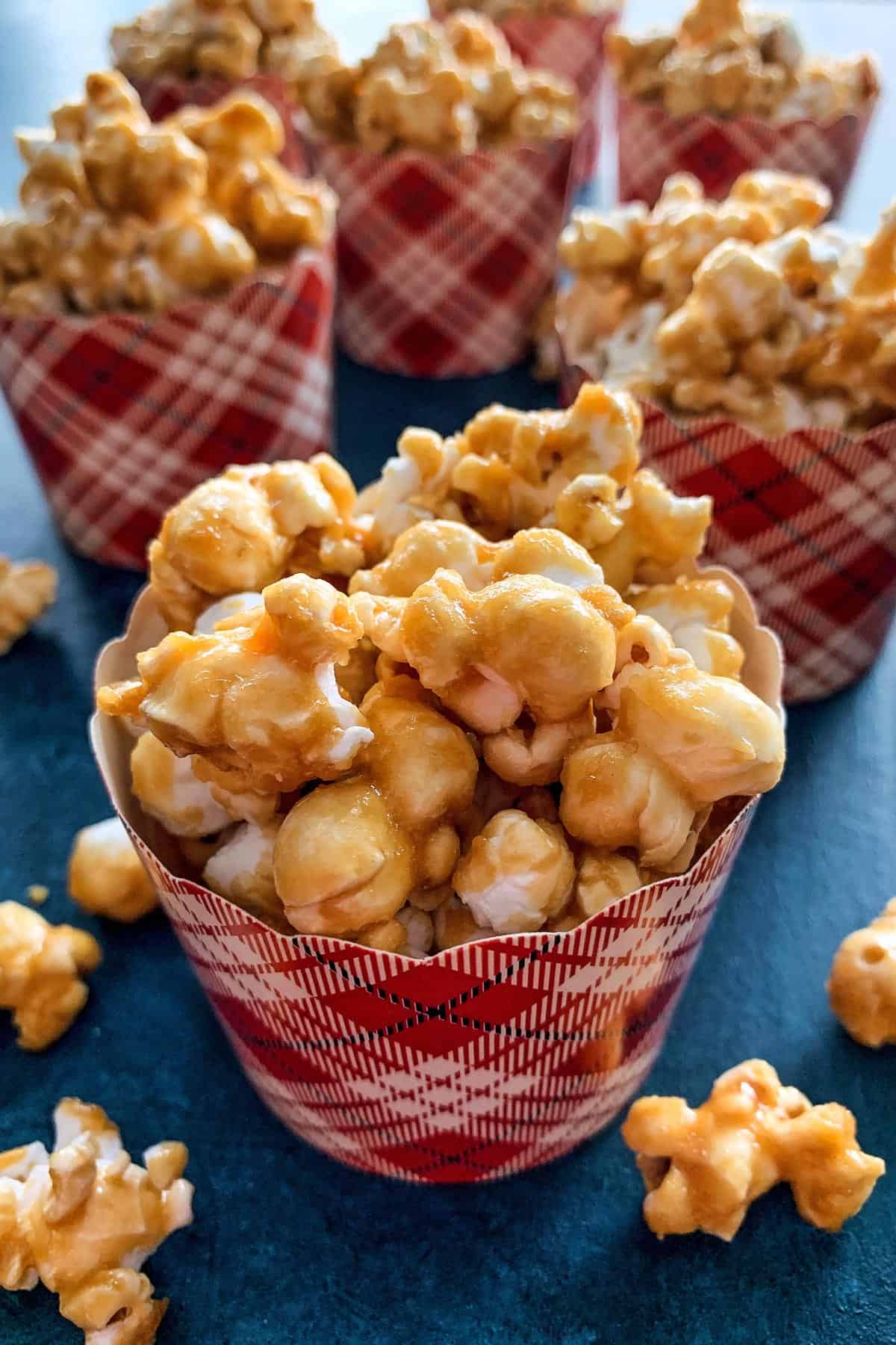 This baked caramel corn is the BEST homemade caramel popcorn recipe! It's crispy, sweet, buttery perfection. Great for gifting and snacking! caramel corn in festive paper baking cups, for gifting