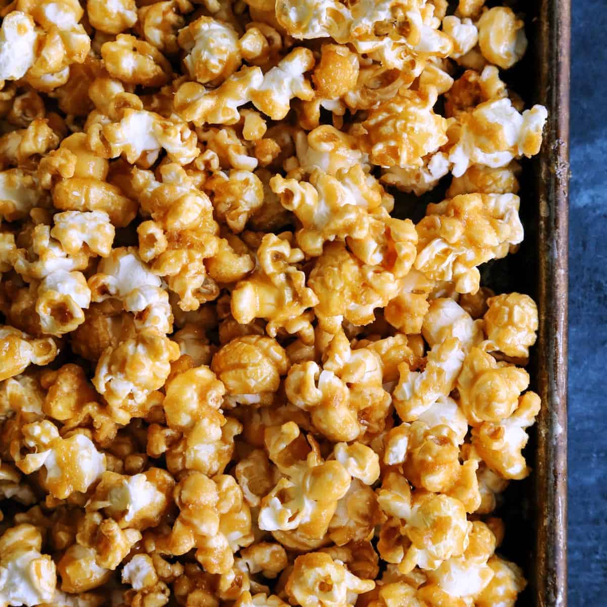 This baked caramel corn is the BEST homemade caramel popcorn recipe! It's crispy, sweet, buttery perfection. Great for gifting and snacking! caramel corn on rimmed pan