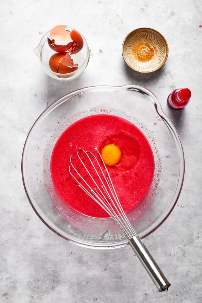 Overhead view of egg added to red velvet cake batter