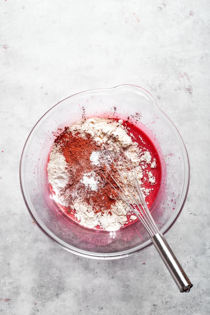 Overhead view of dry ingredients added to red velvet cake batter
