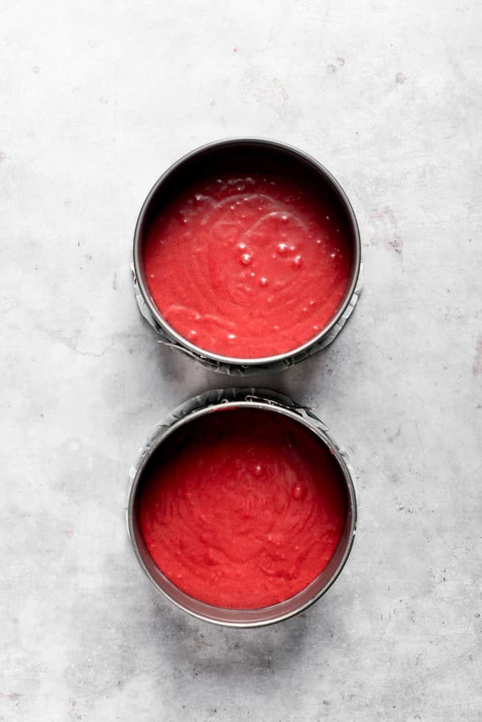Overhead view of red velvet cake batter in pans