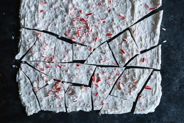 Creamy, minty peppermint bark is easy to make for the holidays with only 3 ingredients! This Christmas candy bark makes a great edible gift. Overhead view of a sheet of peppermint bark partially broken into pieces.