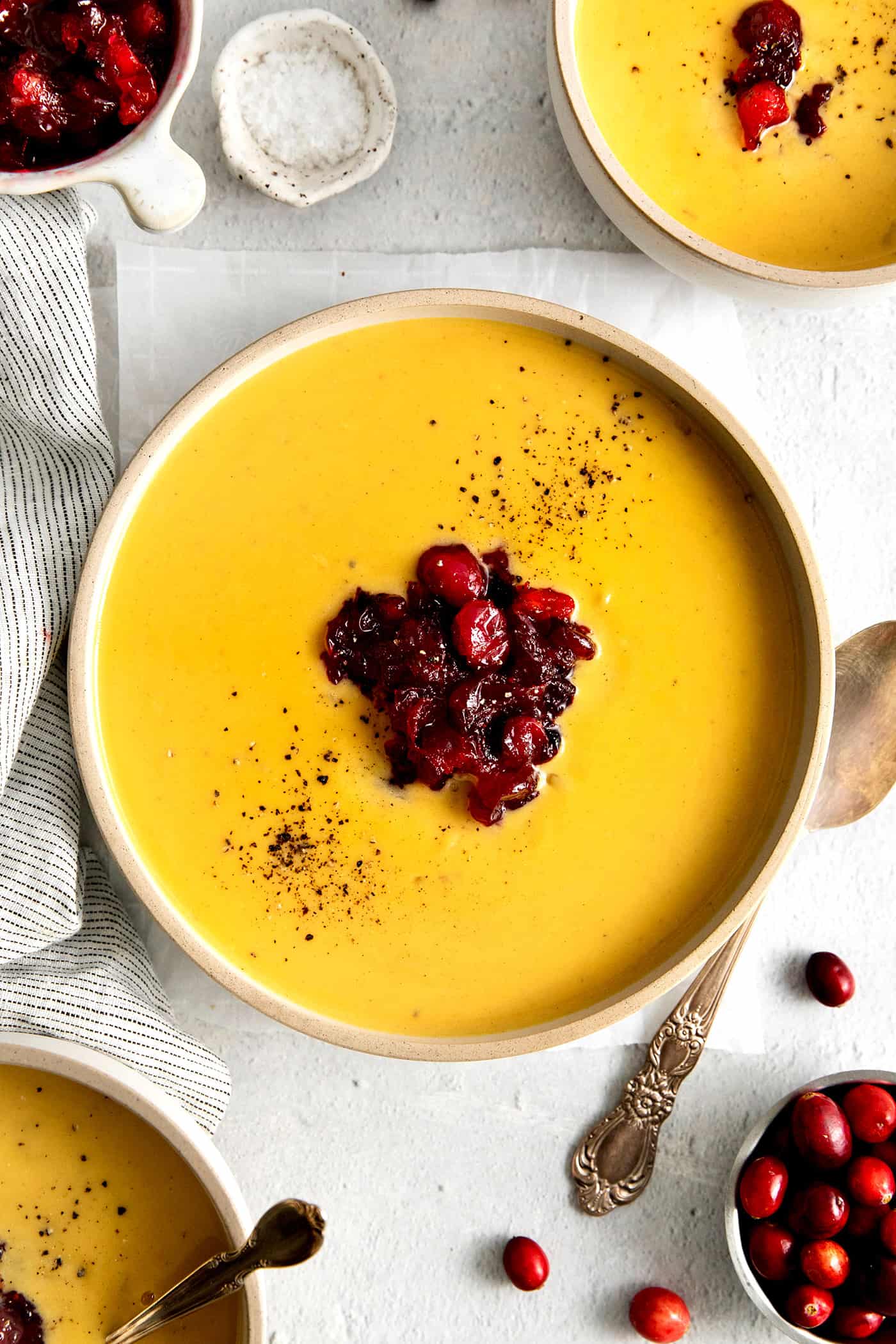This Creamy Squash Soup with Cranberry Relish is made with squash, cream, warm spices and finished with a tart cranberry topping. Overhead view of a bowl of squash soup with cranberry relish