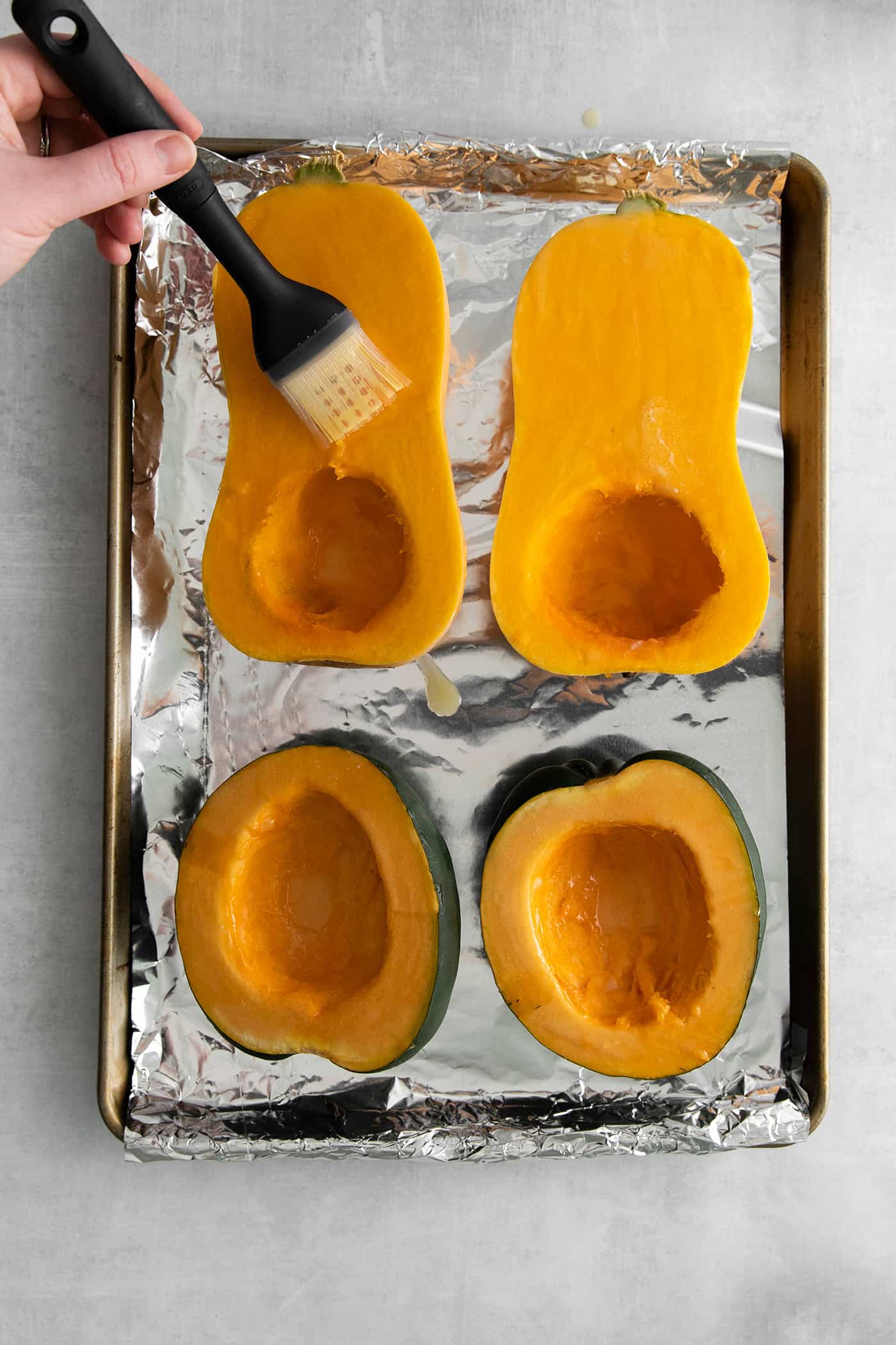 This Creamy Squash Soup with Cranberry Relish is made with squash, cream, warm spices and finished with a tart cranberry topping. Cut squash being brushed with melted butter