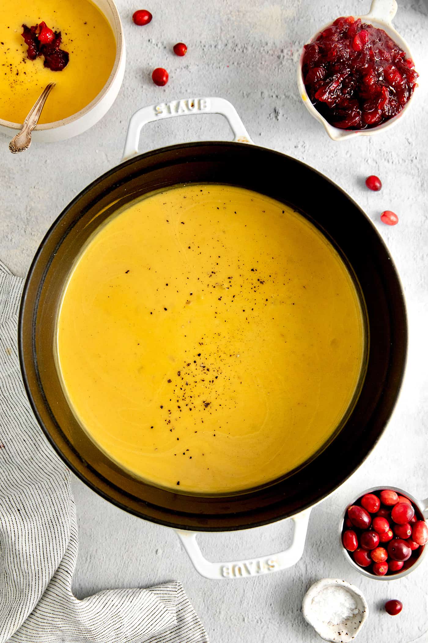 This Creamy Squash Soup with Cranberry Relish is made with squash, cream, warm spices and finished with a tart cranberry topping. Overhead view of squash soup in a pot