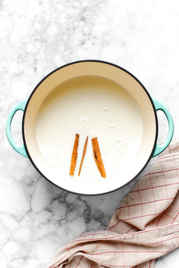 This vanilla steamer recipe combines warm milk with cinnamon, vanilla and almond extract for a cozy drink to savor all winter long. Overhead view of cinnamon sticks infusing in warm milk