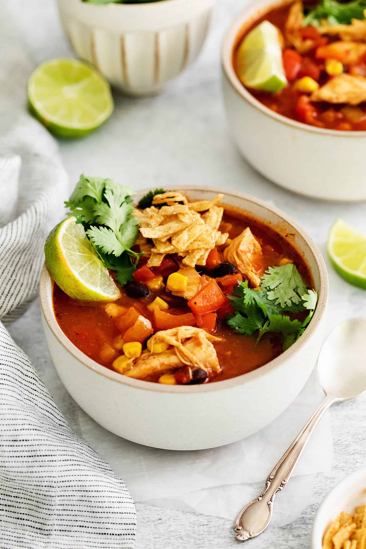 This easy chicken tortilla soup recipe is loaded with Mexican-style flavor, ready in 40 minutes! A perfect one pot soup recipe for weeknights! Angled view of a bowl of chicken tortilla soup topped with lime and cilantro