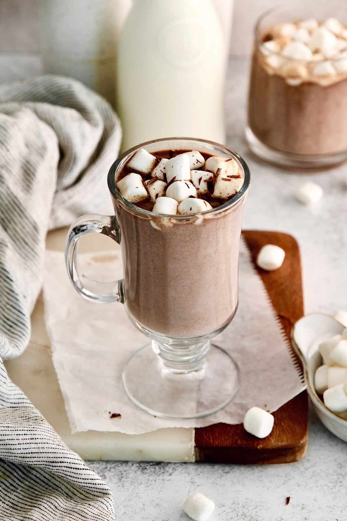 This recipe for homemade hot chocolate makes the creamiest and most decadent hot cocoa ever! It's easy to make and impossible to resist. Hot chocolate in glass mug with marshmallows and shaved chocolate for garnish