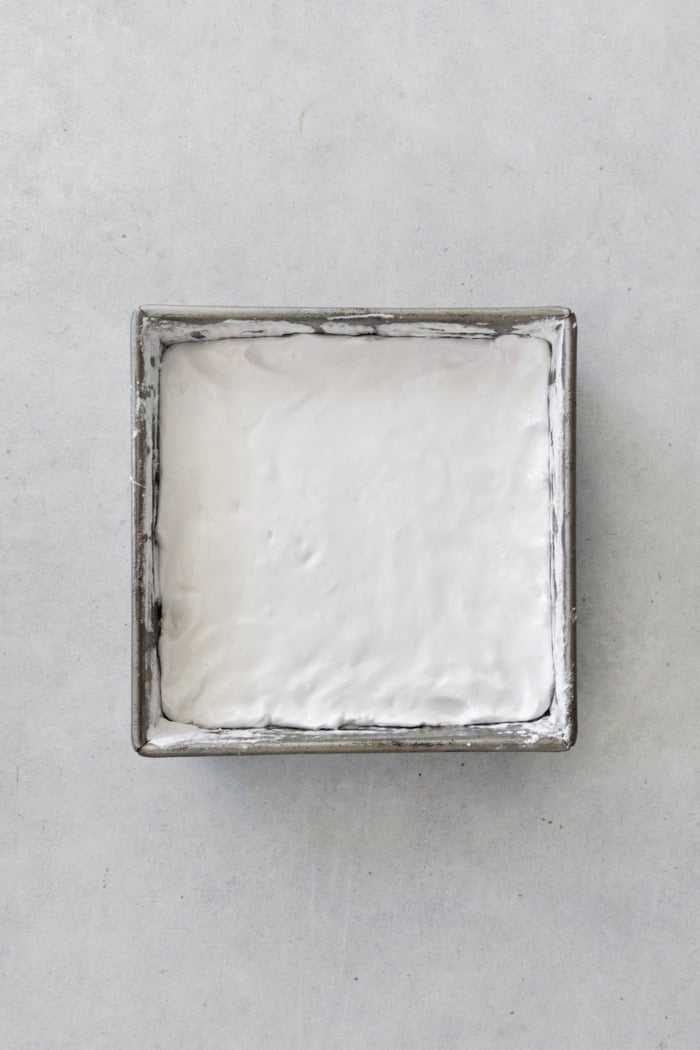 Homemade marshmallows are easier than you think! This recipe yields perfect fluffy marshmallows that are SO much better than store-bought. Overhead view of marshmallow mixture spread into square pan