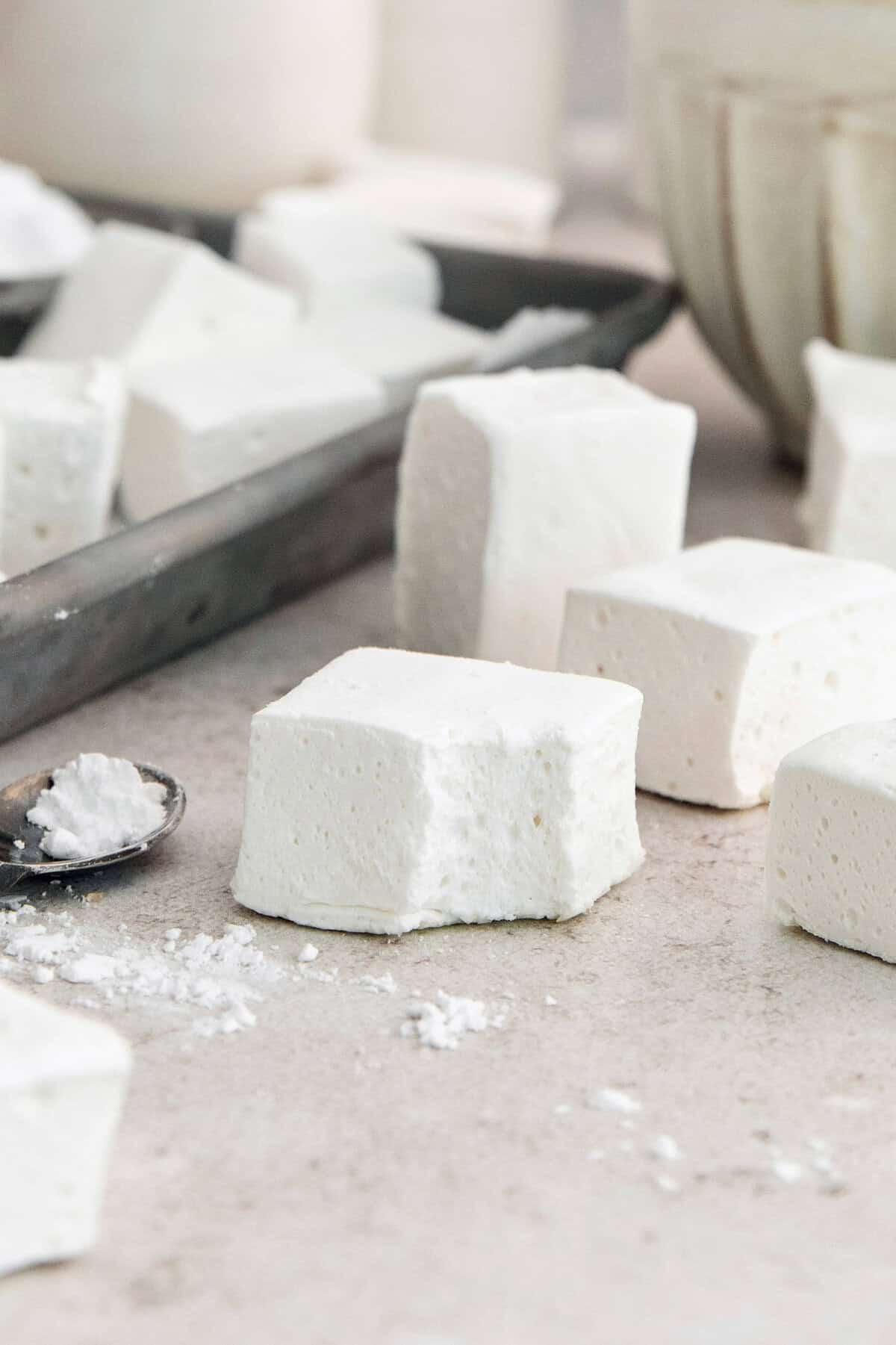 Homemade marshmallows are easier than you think! This recipe yields perfect fluffy marshmallows that are SO much better than store-bought. Fluffy homemade marshmallows on countertop, with one bitten into on the corner