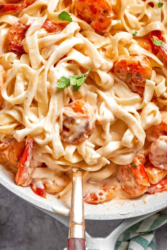 Rich without being heavy, garlicky with just a bit of heat, this Creamy Shrimp Pasta is a restaurant-worthy meal ideal for a date-night-in! Creamy shrimp pasta in skillet with serving spoon.