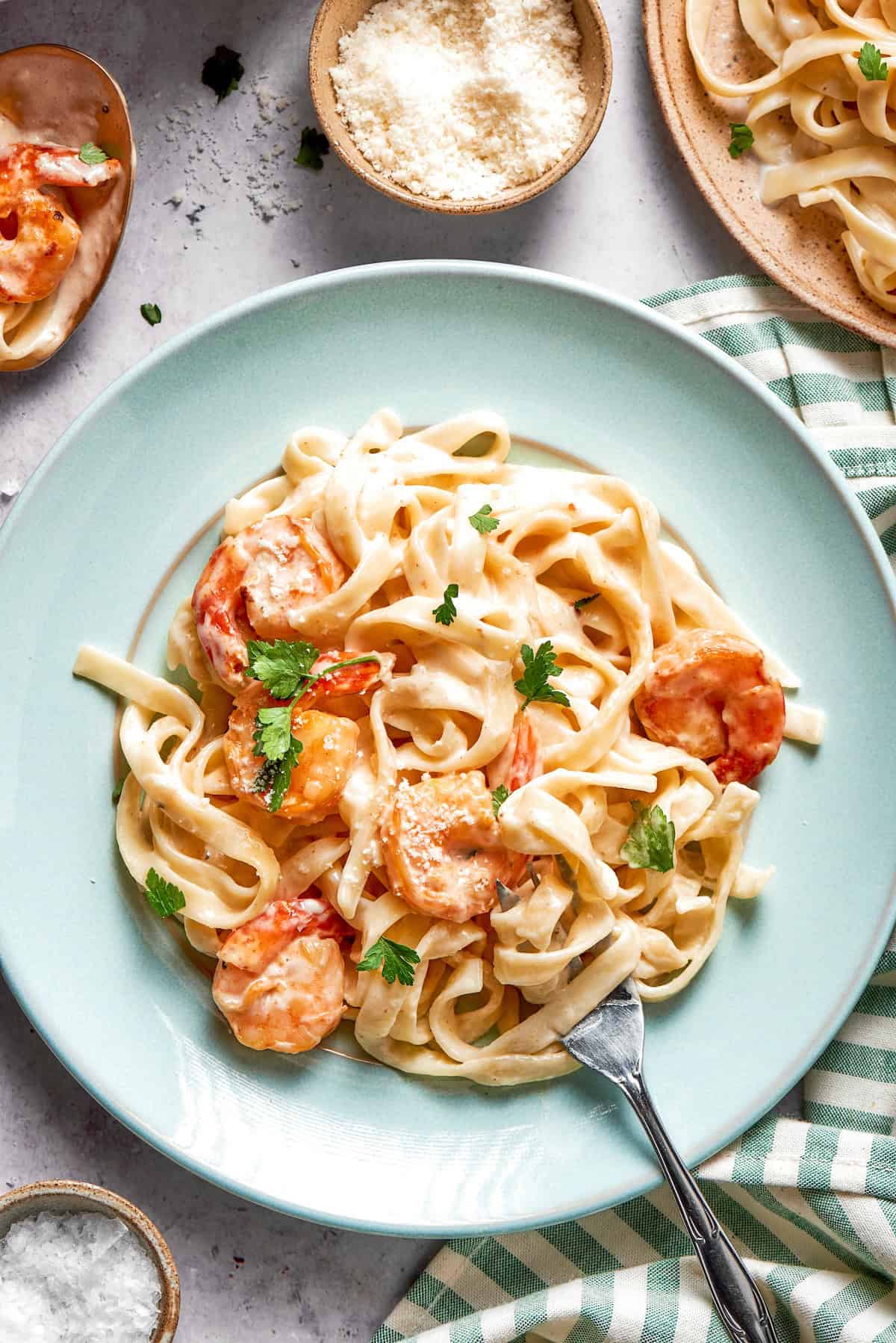Rich without being heavy, garlicky with just a bit of heat, this Creamy Shrimp Pasta is a restaurant-worthy meal ideal for a date-night-in! Fork on plate of creamy shrimp pasta.