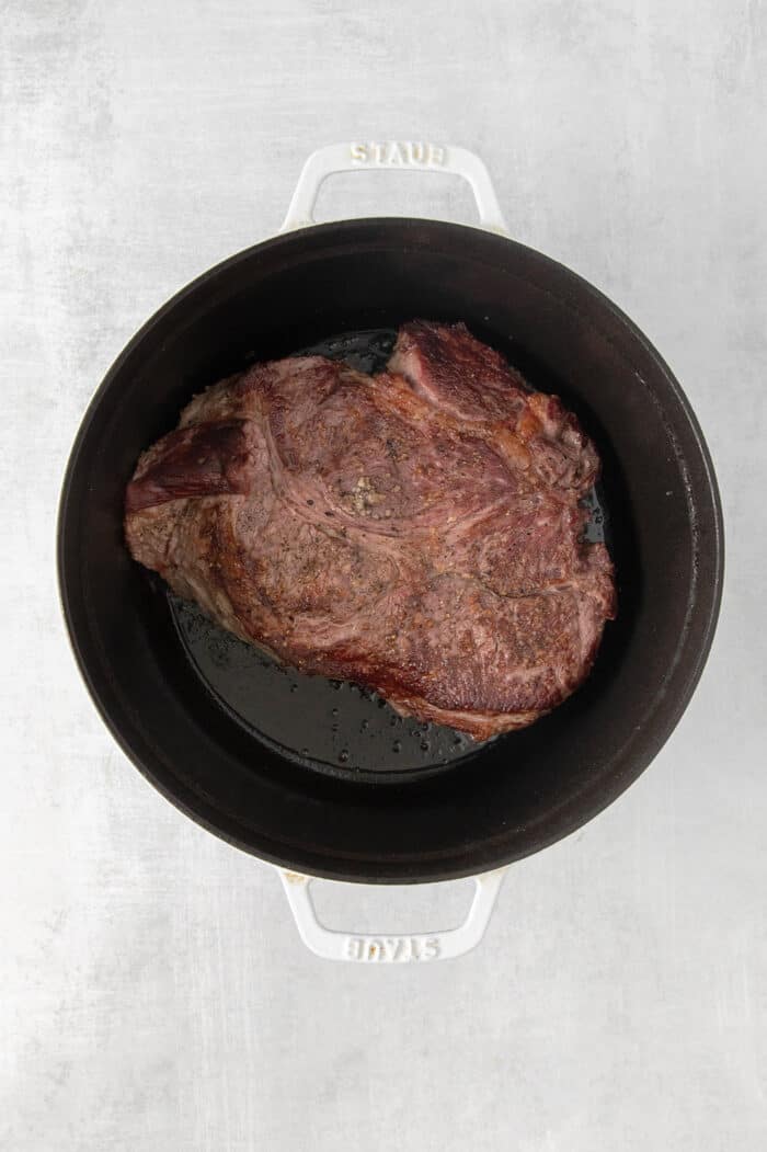 Made with chuck roast, potatoes, carrots, and onions in a beef broth, this Classic Pot Roast is comfort food at its finest. Hearty & filling! Overhead view of a chuck roast in a stock pot
