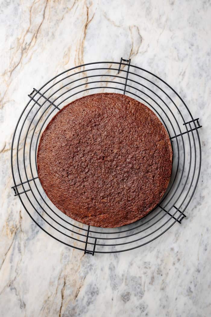 This classic German Chocolate Cake recipe is a moist, rich three-layer chocolate cake topped with a nutty coconut-pecan frosting. Perfection! Overhead view of German chocolate cake round cooling on rack