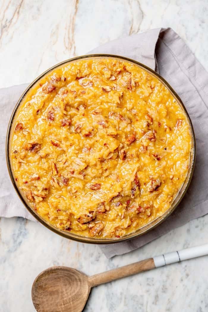 This classic German Chocolate Cake recipe is a moist, rich three-layer chocolate cake topped with a nutty coconut-pecan frosting. Perfection! Overhead view of coconut pecan frosting
