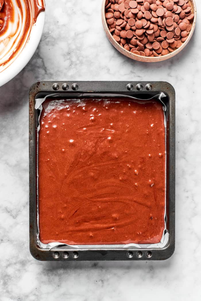 These fudgy brownies are a cinch to make with everyday pantry ingredients and the intensely fudgy texture and chocolate flavor is awesome! Overhead view of brownie batter in parchment-lined pan