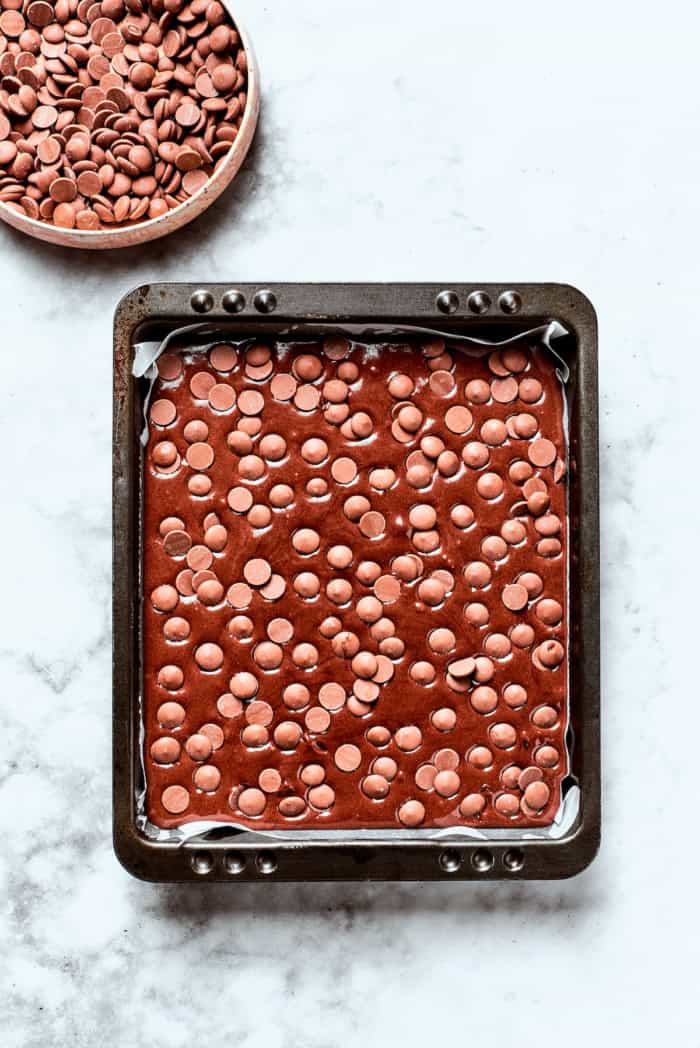 These fudgy brownies are a cinch to make with everyday pantry ingredients and the intensely fudgy texture and chocolate flavor is awesome! Overhead view of chocolate chips added to pan of brownie batter