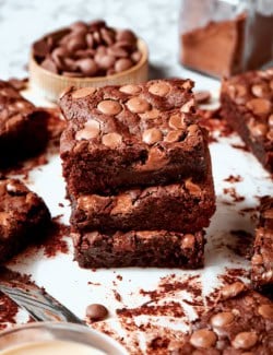 Stack of 3 fudgy brownies on parchment paper
