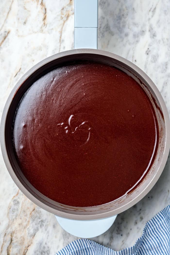 Three layers of dark chocolate cake are smothered with rich fudgy frosting, creamy caramel, and crispy salted pecans. So good! Chocolate frosting in saucepan.