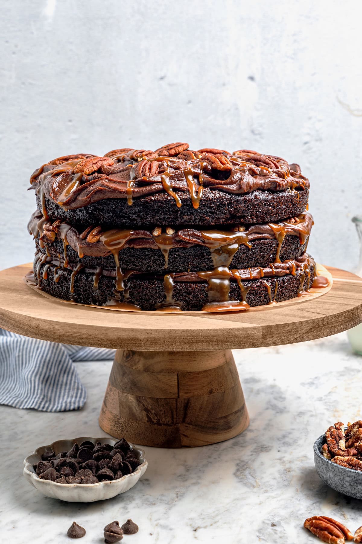 Three layers of dark chocolate cake are smothered with rich fudgy frosting, creamy caramel, and crispy salted pecans. So good! Whole turtle cake on cake stand.