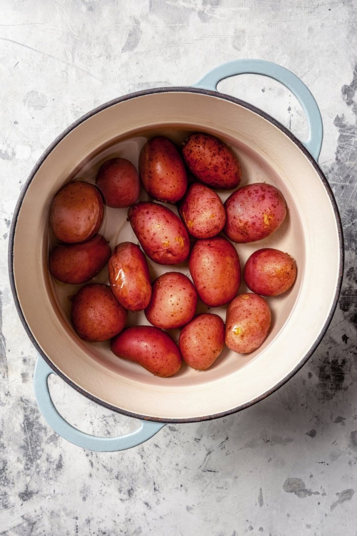 With smoky red potatoes and a rich blue cheese vinaigrette, this grilled potato salad recipe is so delicious, it might just steal the show! Overhead view of red potatoes in pot