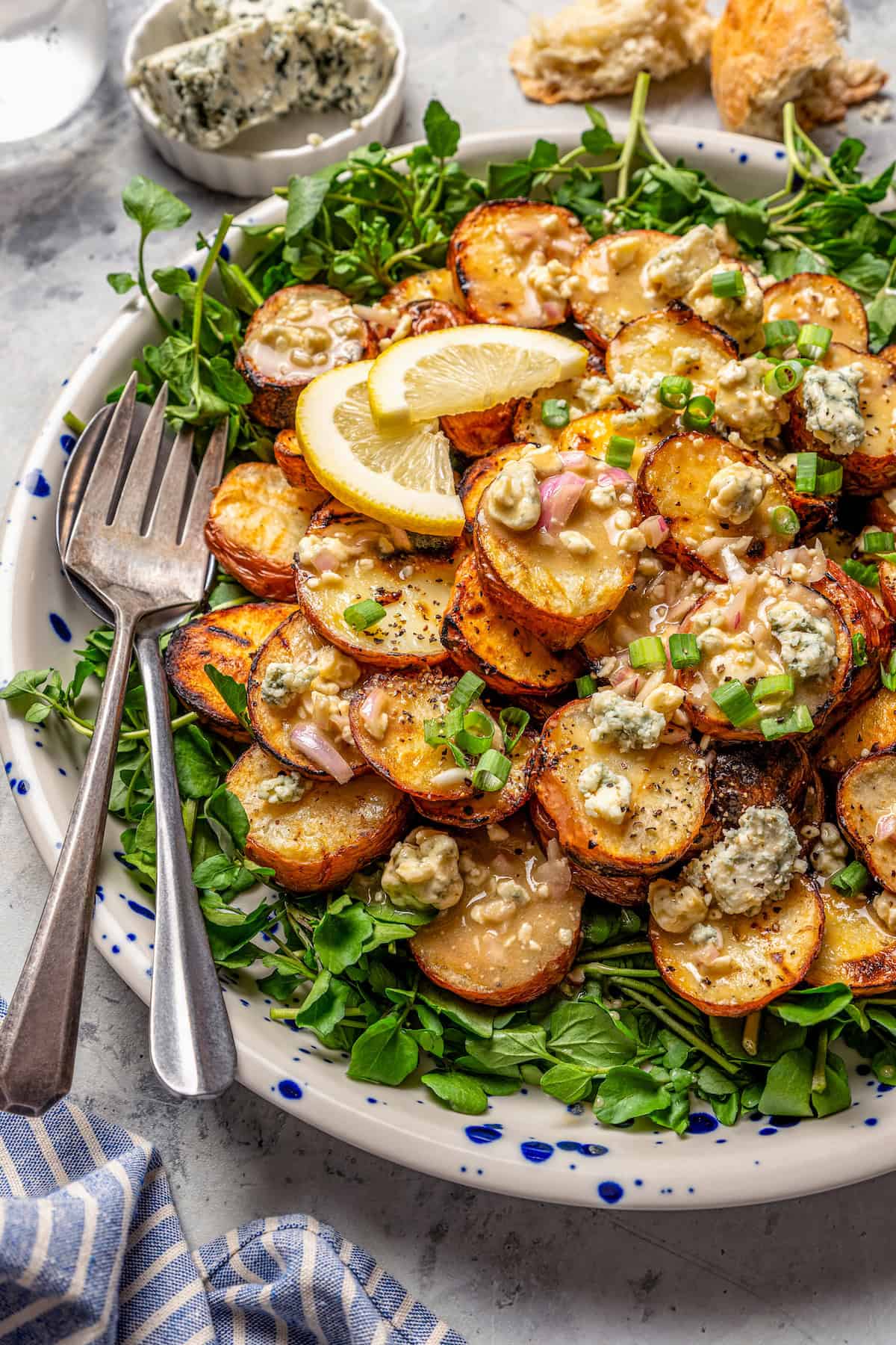 With smoky red potatoes and a rich blue cheese vinaigrette, this grilled potato salad recipe is so delicious, it might just steal the show! Grilled potato salad with blue cheese vinaigrette on platter with two forks