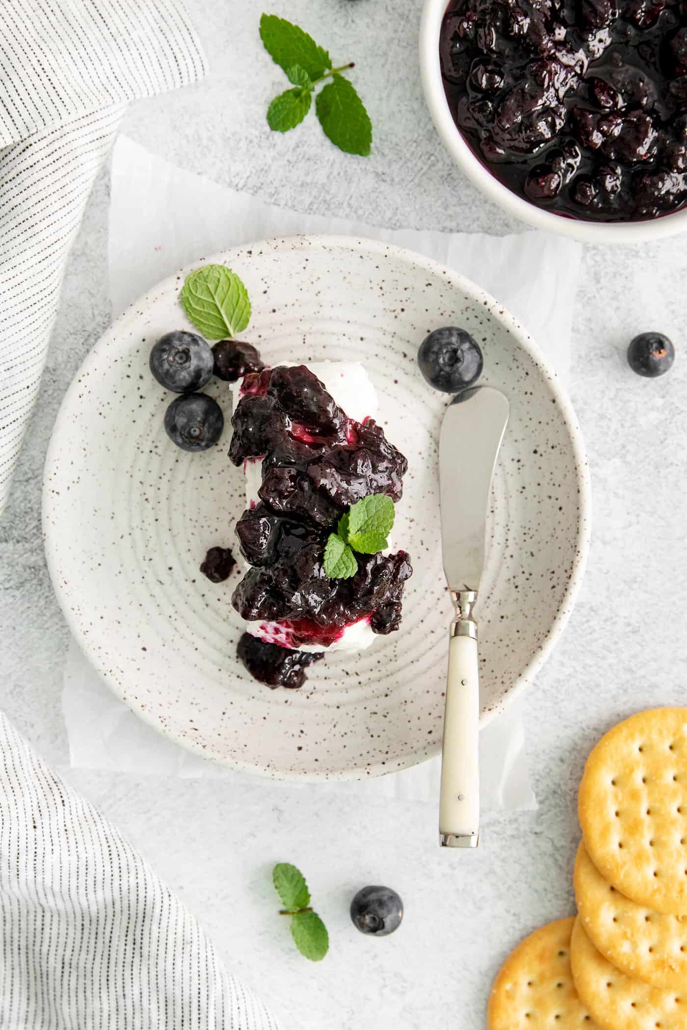 Made with just 4 ingredients, this Homemade Blueberry Jam with Mint is dark and fruity, with a sweet but cool and refreshing flavor. Overhead view of ice cream topped with blueberry jam