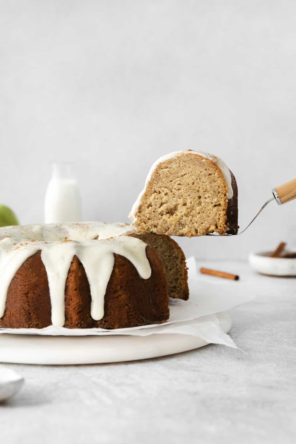 This easy apple bundt cake was made for fall baking! A moist and fluffy apple cake drizzled with an irresistible brown butter vanilla glaze. An apple bundt cake with a slice on a serving utensil