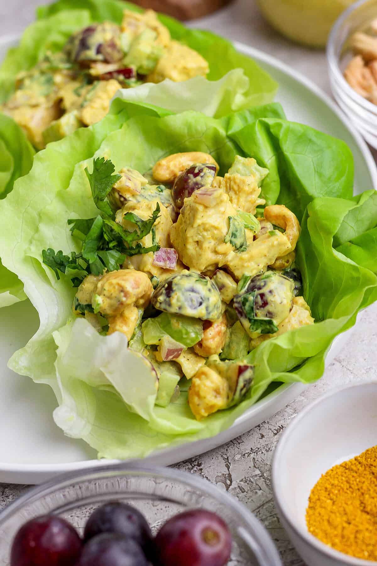 This easy Curry Chicken Salad recipe is the perfect blend of sweet and savory, with juicy grapes, cashews, and a creamy curried dressing. Curry chicken salad in lettuce cups on plate