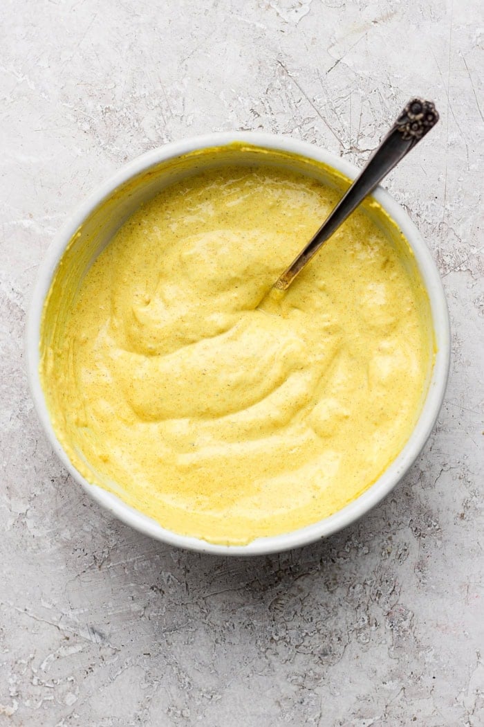 This easy Curry Chicken Salad recipe is the perfect blend of sweet and savory, with juicy grapes, cashews, and a creamy curried dressing. Curried yogurt dressing in bowl with spoon